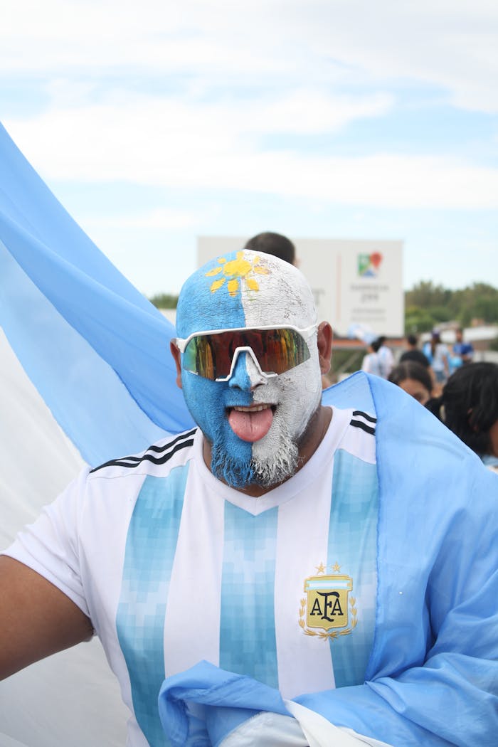 Vibrant portrait of an enthusiastic Argentina football fan with face paint and flag draped.