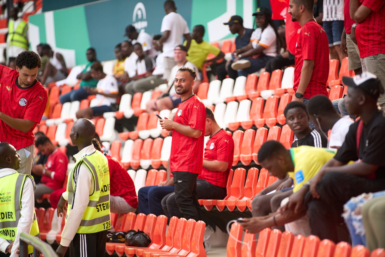 Diverse group of soccer fans wearing red jerseys at a lively stadium event.