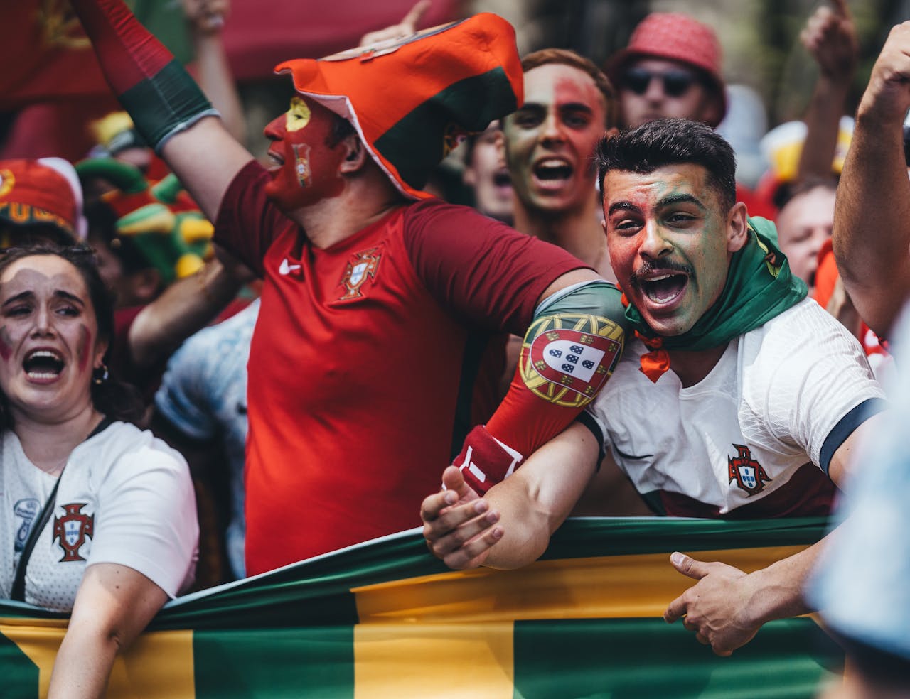 who-we-are Passionate Portuguese soccer fans celebrating outdoors with flags and face paint.