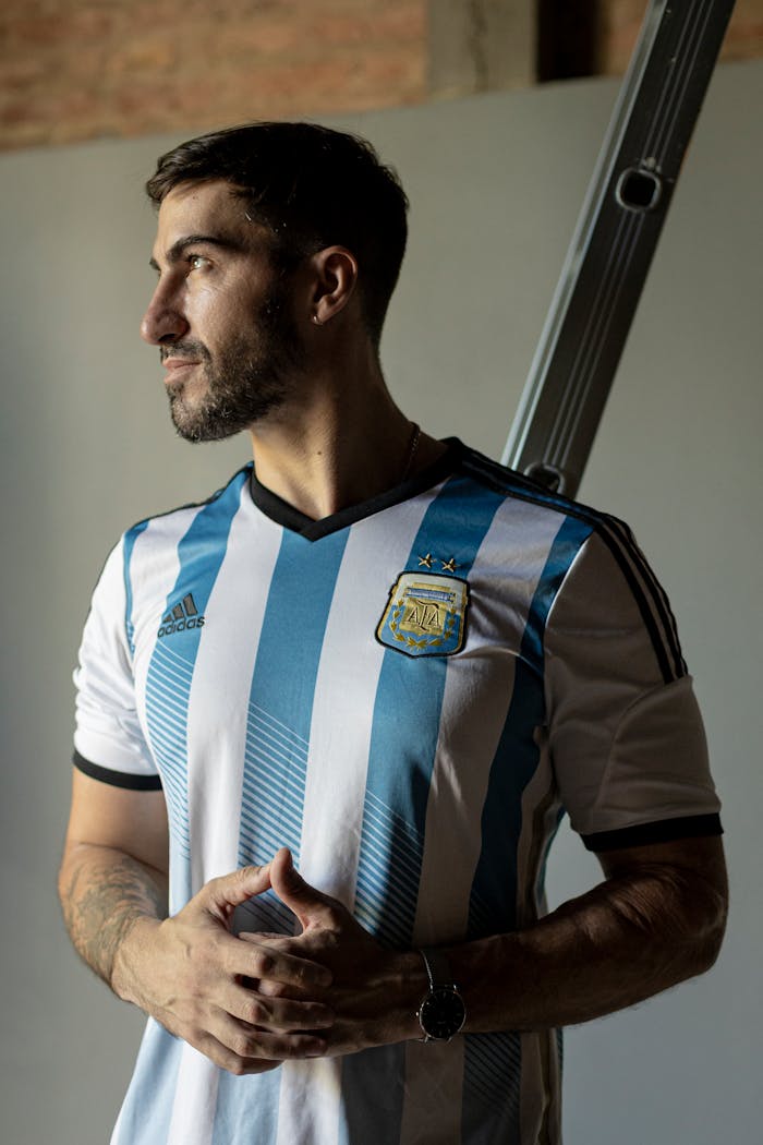 Adult male wearing Argentina football jersey, standing indoors with natural light.