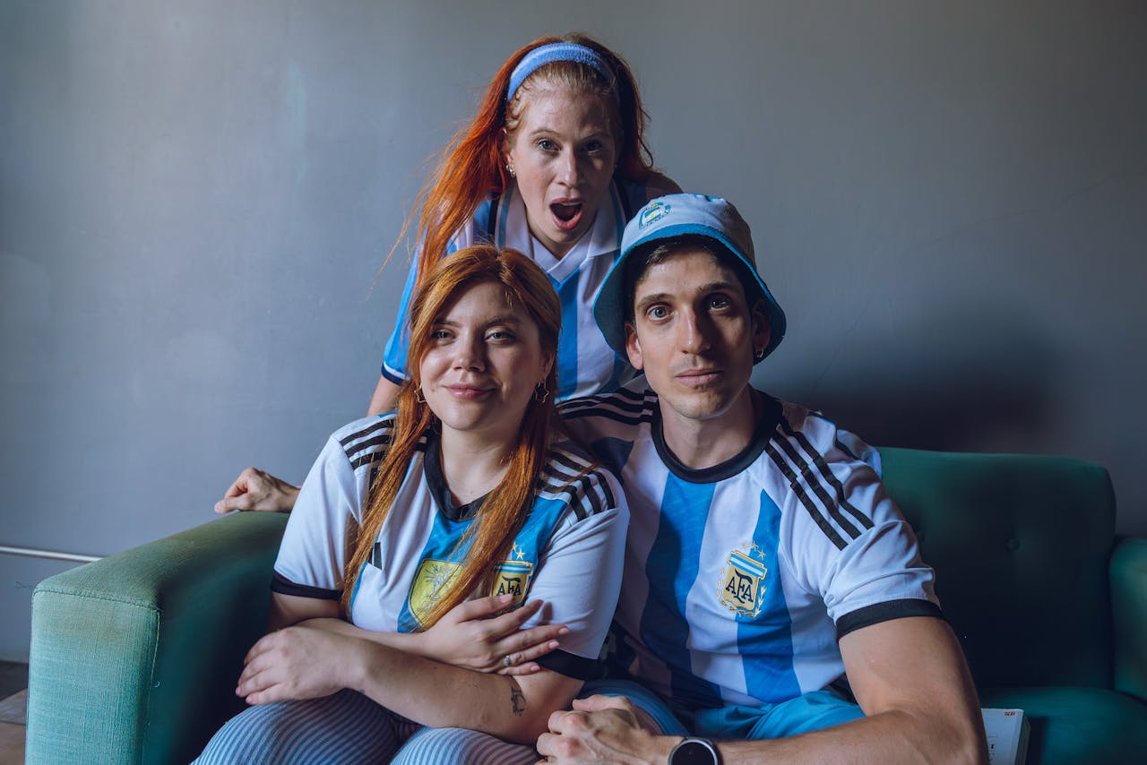 services-01 Group of fans in Argentina soccer jerseys expressing excitement indoors.